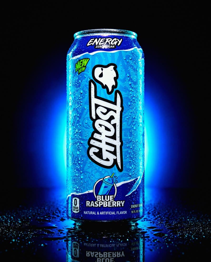 Energy drink can shot low against wet asphalt, dusk light, condensation beading